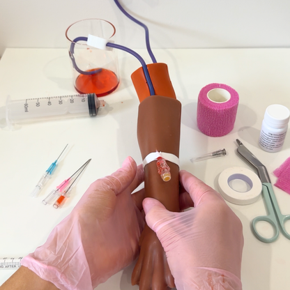 IV Canine Leg Training Kit with a realistic dog leg training arm, blood bag, syringe, bandages, and small medical accessories on a pink background with the text 'IV Canine Leg Training Kit' and 'VET NURSE SCHOOL'.