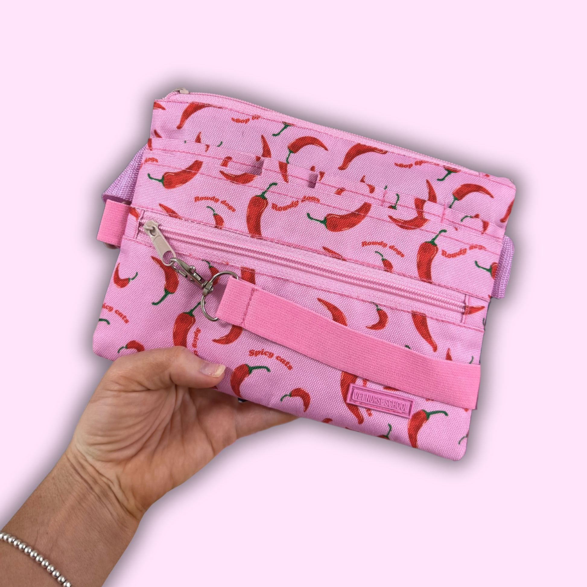 Pink vet nurse fanny bag pouch with red chili pepper pattern held by a hand on a light pink background