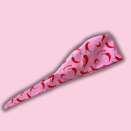 Pink scrub hat cap headband with red chili pepper pattern on a pink background