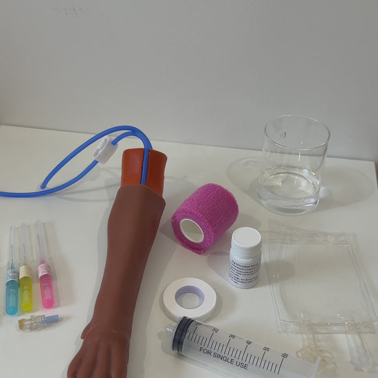 IV Canine Leg Training Kit with a realistic dog leg training arm, blood bag, syringe, bandages, and small medical accessories on a pink background with the text 'IV Canine Leg Training Kit' and 'VET NURSE SCHOOL'.