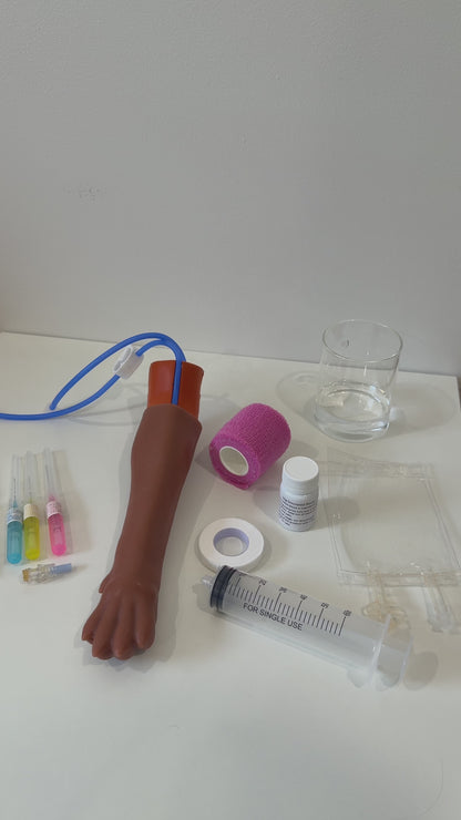 IV Canine Leg Training Kit with a realistic dog leg training arm, blood bag, syringe, bandages, and small medical accessories on a pink background with the text 'IV Canine Leg Training Kit' and 'VET NURSE SCHOOL'.