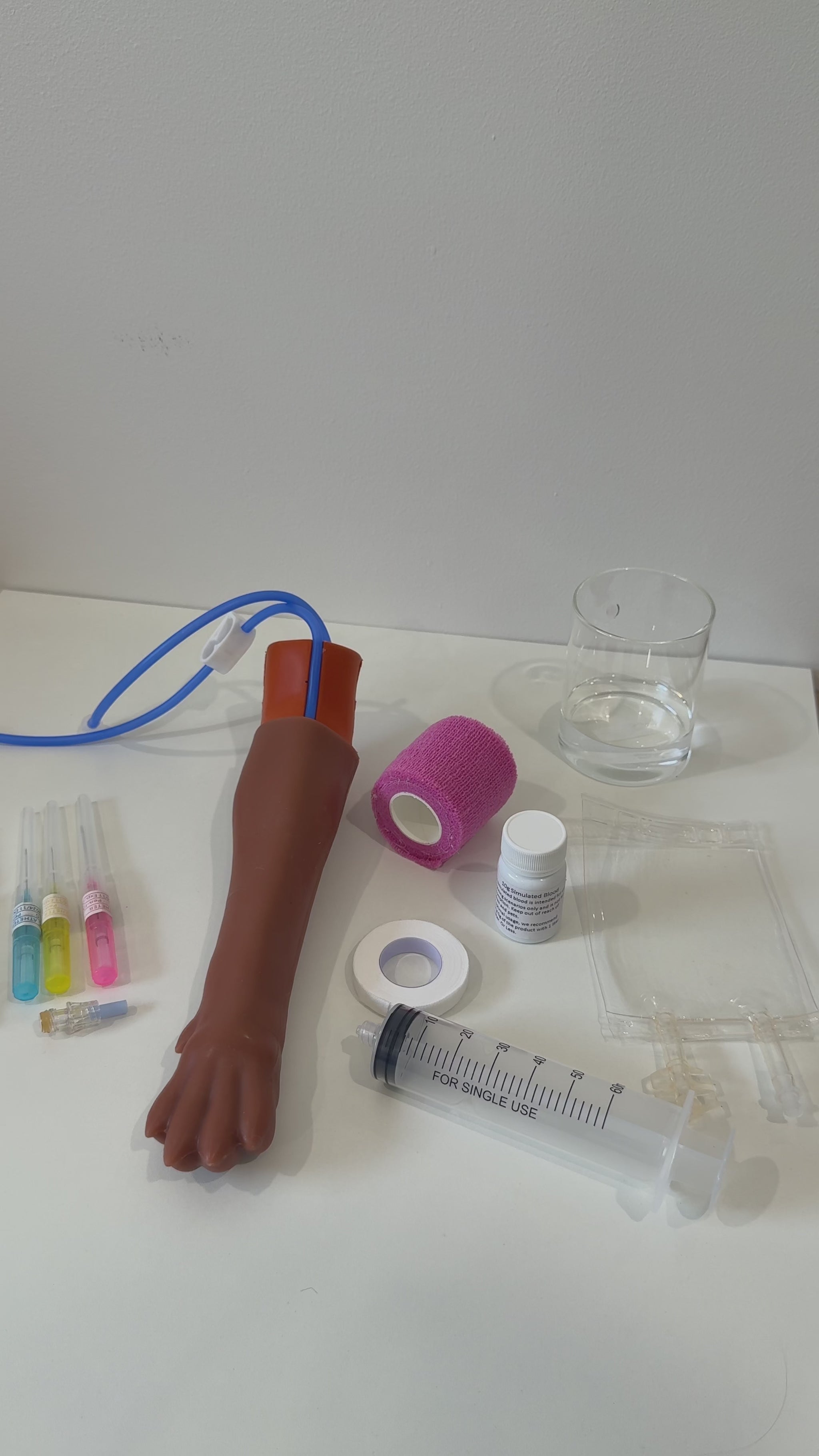 IV Canine Leg Training Kit with a realistic dog leg training arm, blood bag, syringe, bandages, and small medical accessories on a pink background with the text 'IV Canine Leg Training Kit' and 'VET NURSE SCHOOL'.